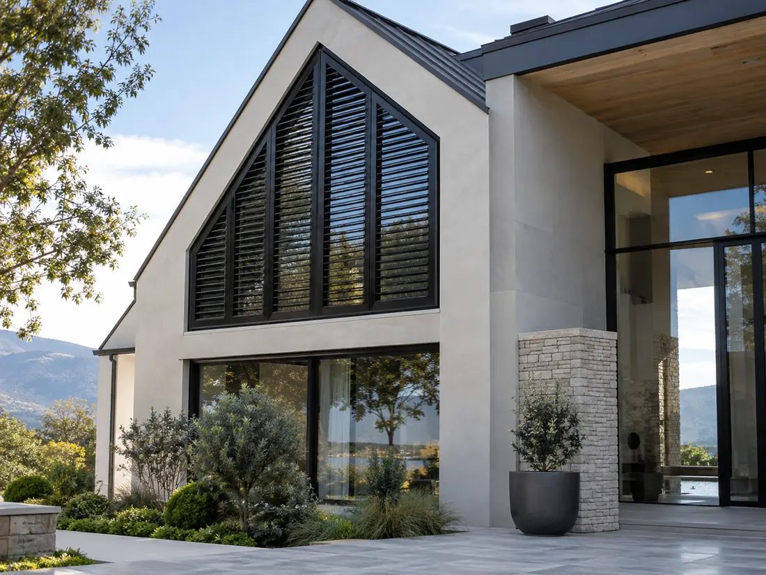 Schwarze Aluminium-Außen-Shutters nach Maß im Giebel eines hellen Hauses