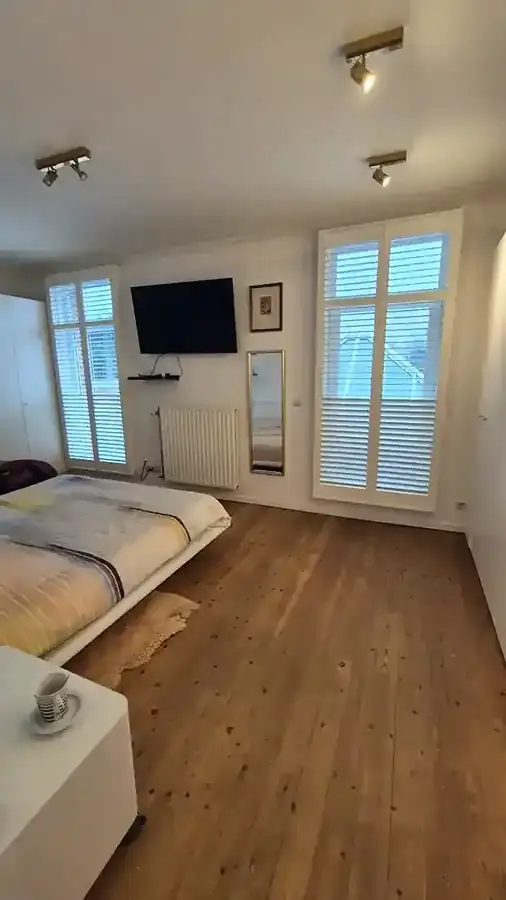 Des shutters blancs dans une chambre à Balen