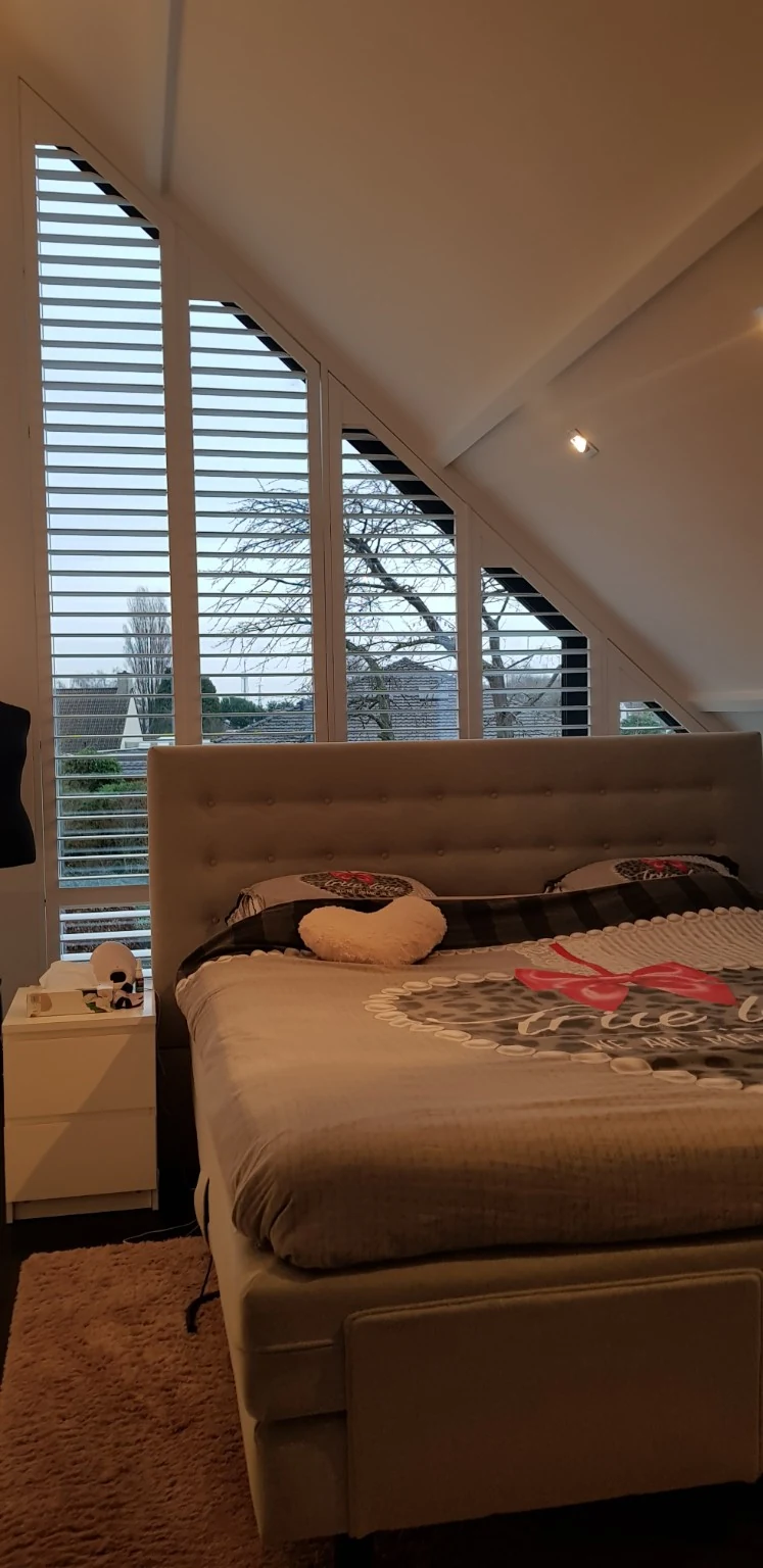White shutters along the sloping bedroom window in Haacht, with 89 mm louvres and ClearView — project photo 2