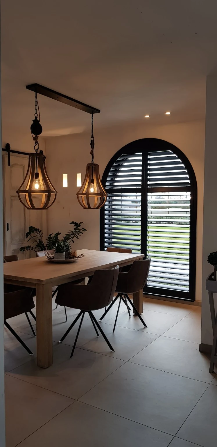 Dunkle Shutters an einem Bogenfenster in Turnhout, mit 76-mm-Lamellen, ClearView und Innenmontage mit Z-Frame.