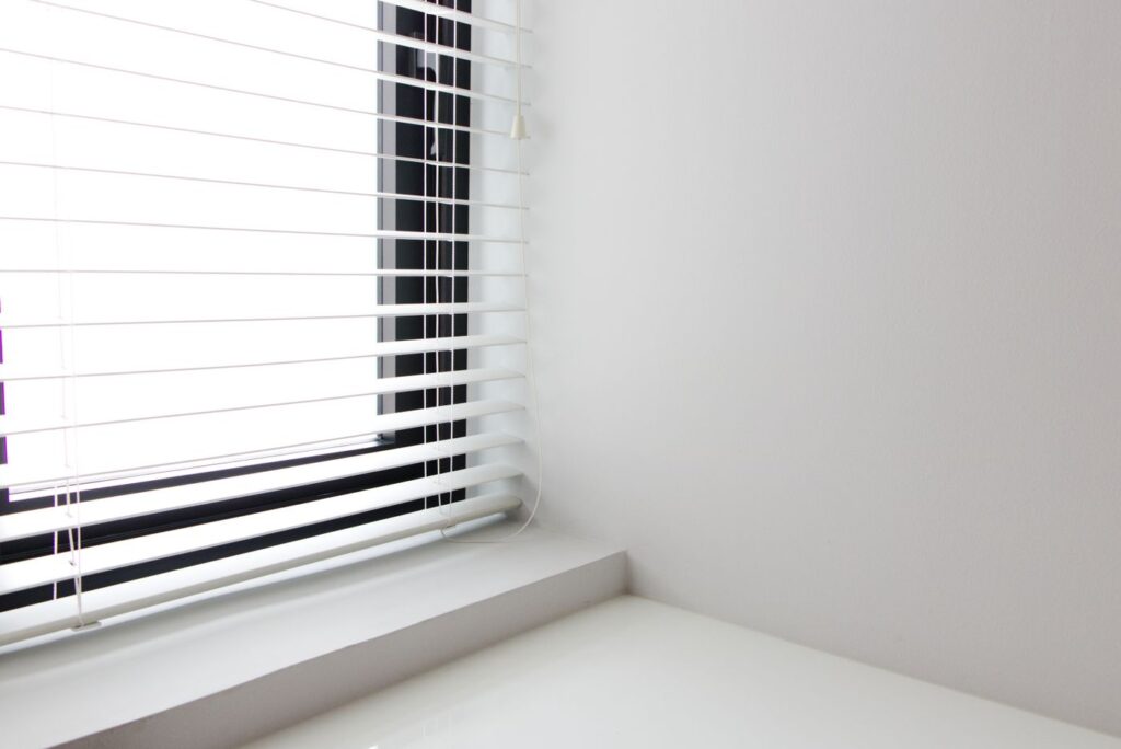 Witte jaloezieën bij een licht raam